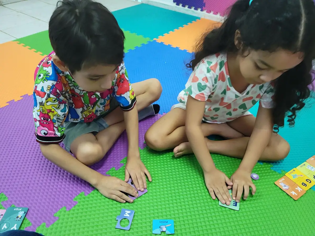 Dos niños formando palabras con tarjetas sobre un tapete de colores