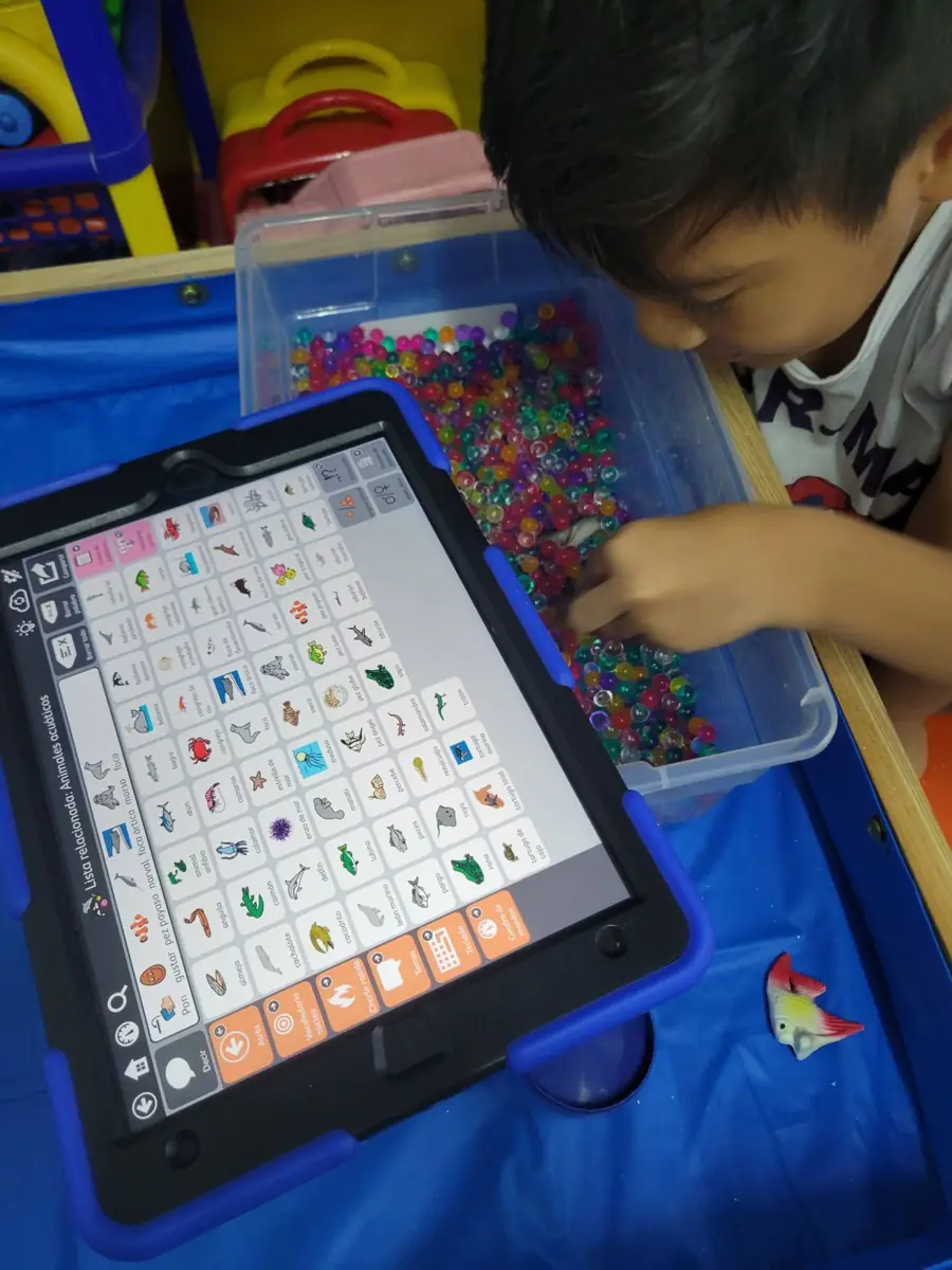 Niño usando una tableta con pictogramas de comunicación aumentativa