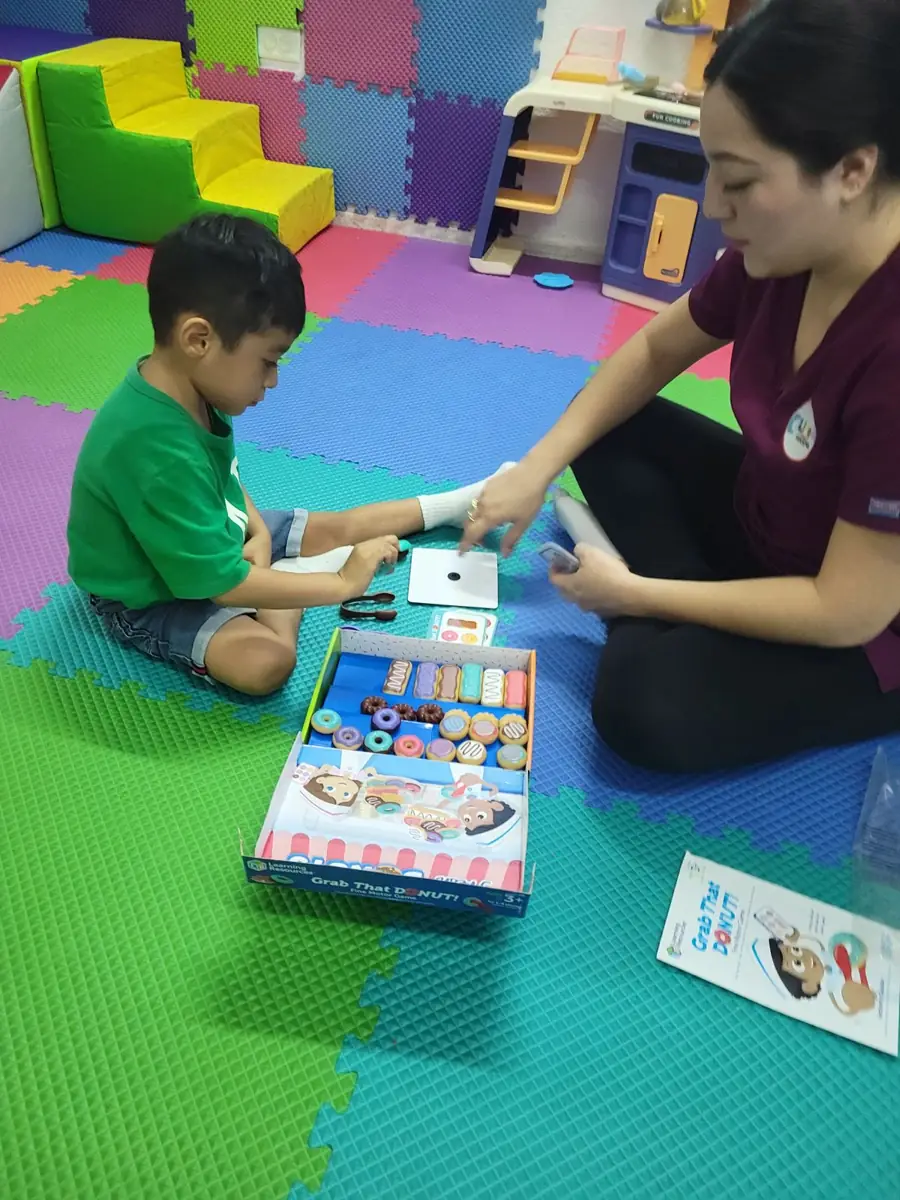 Terapeuta y niño jugando un juego de mesa educativo