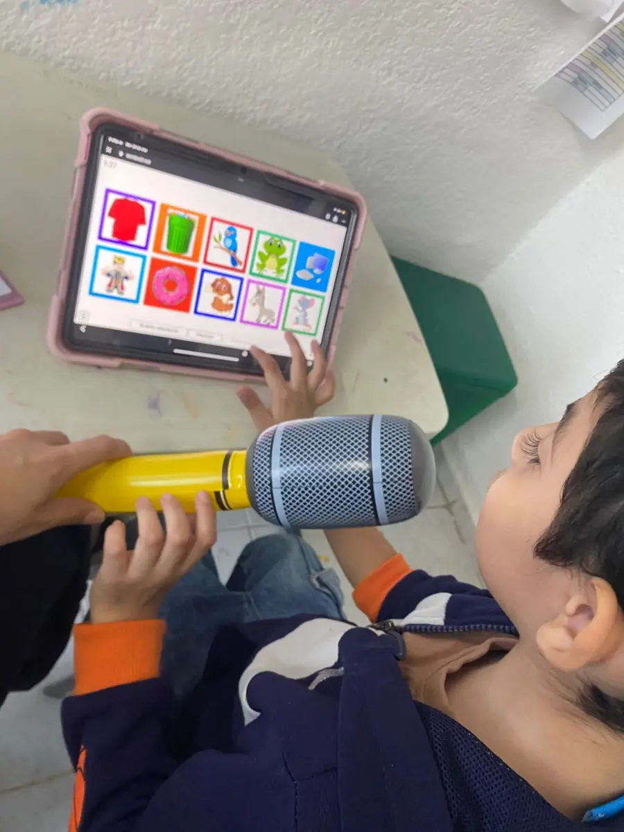 Niño practicando con un micrófono de juguete frente a una tableta